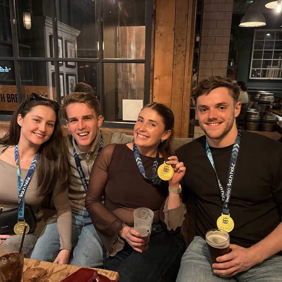 Four runners celebrating in a pub with their Bath Half medals