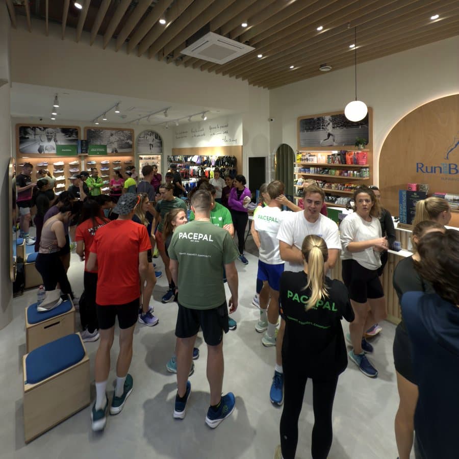 Runners in PacePal t-shirts gathering inside a running shop before a group run